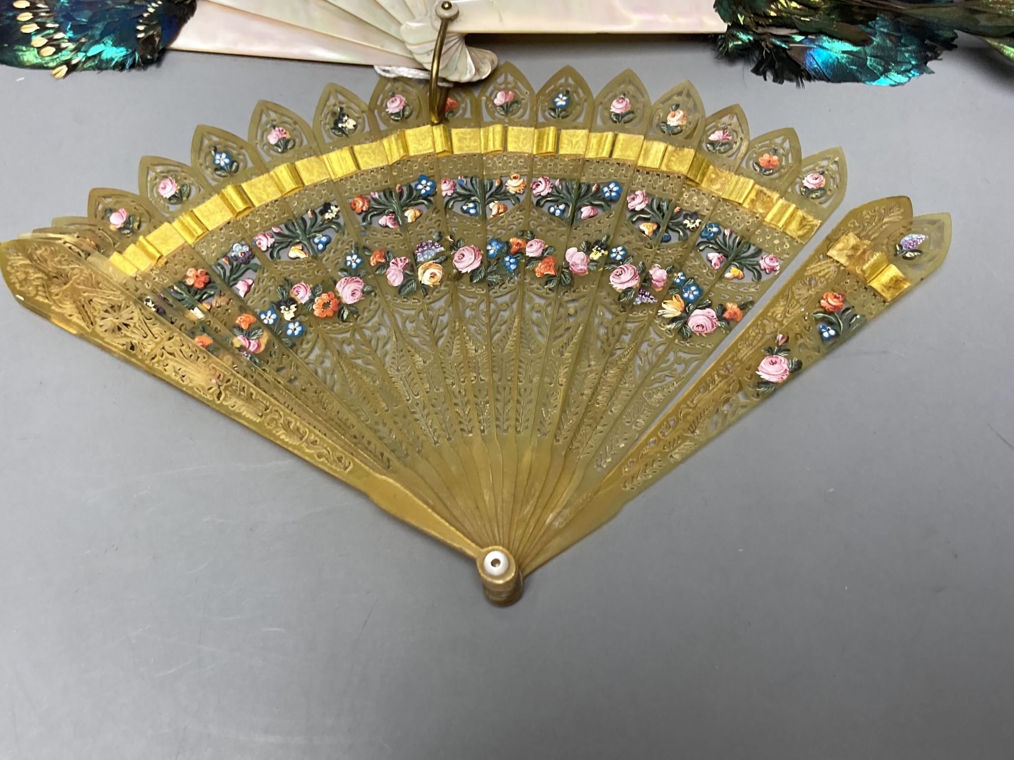 An early 20th century peacock? feather and mother of pearl fan and an early 19th century French painted horn brise fan